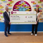 Two people holding a giant cheque for £4535 raised by Winston Solicitors for Leeds Mencap.