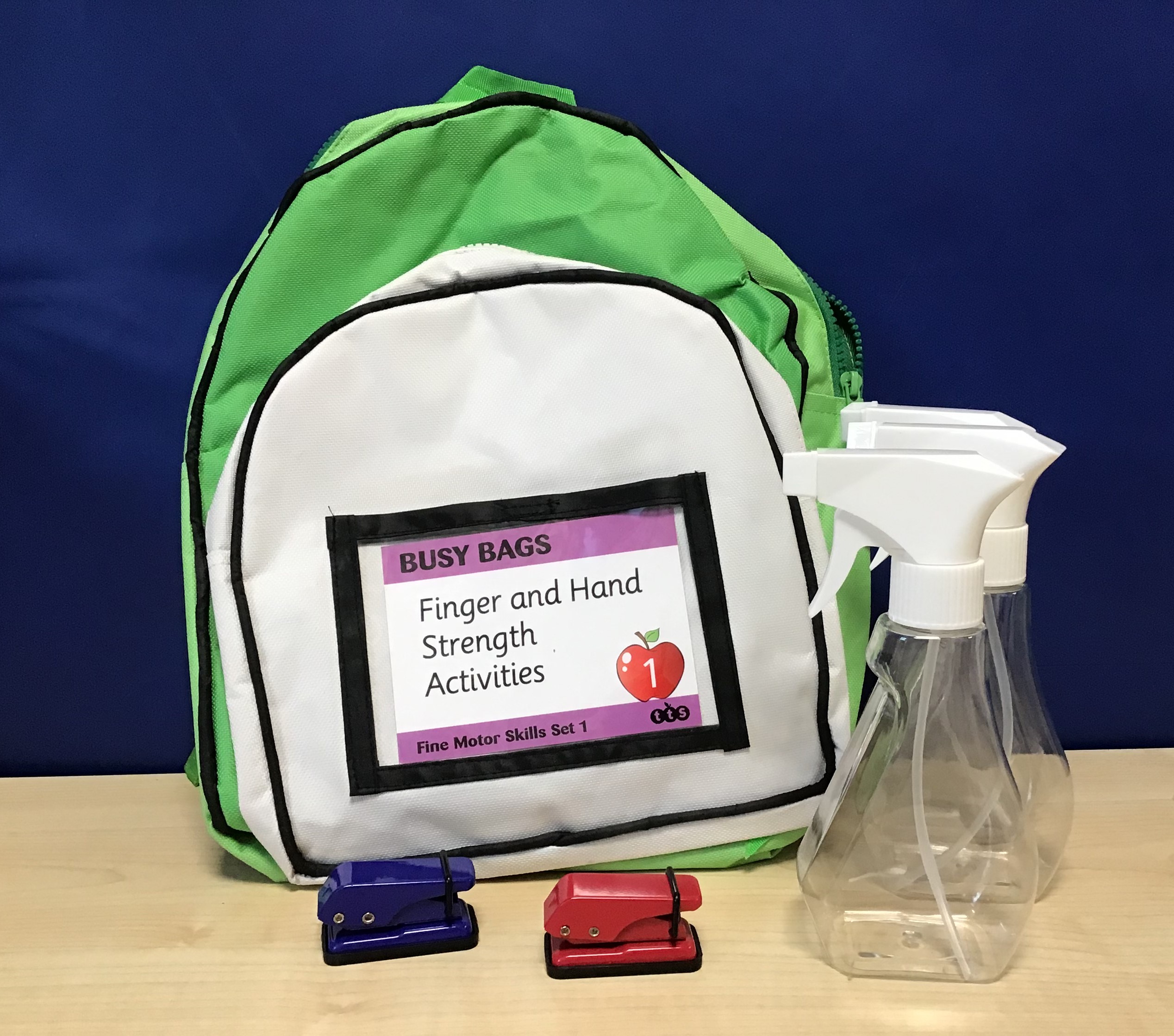 Busy Bags – Fine Motor Skills. Green and white backpack with 3 squirty water bottles and two staplers next to it.