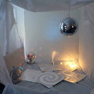 Pop-up white sensory tent with a range of sensory toys inside including a shiny disco ball and a projector.